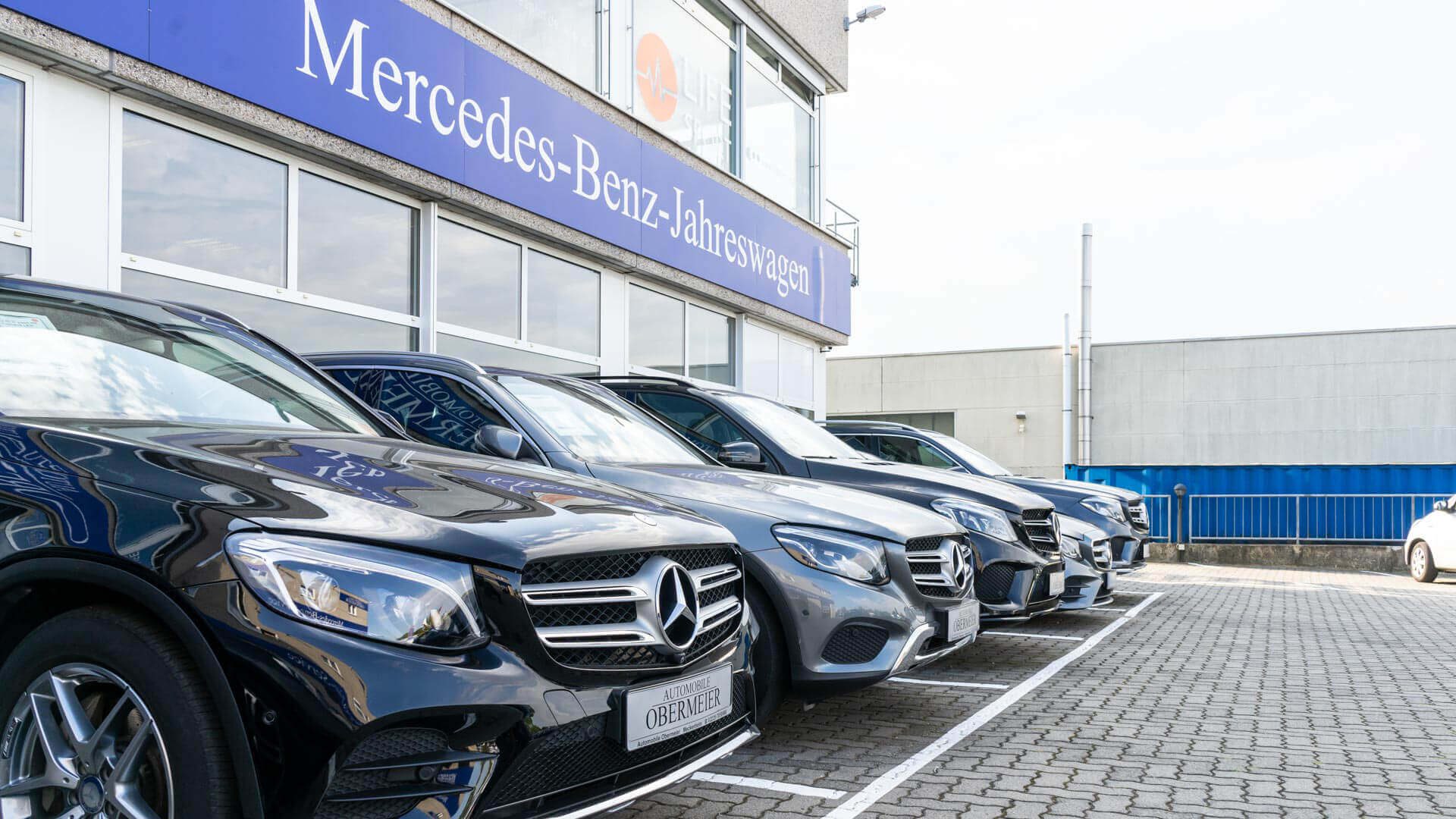 Aufgereihte Gebrauchtfahrzeuge von Mercedes Benz vor Automobile Obermeier Gebäude